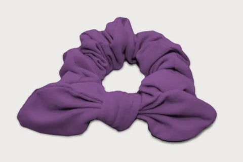 A purple Knotted Bow Scrunchie by Goodnighties, made from soft thermoregulating fabric, is shown on a plain white background—an elegant American-made hair accessory.