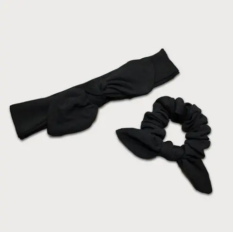The Goodnighties Matching Knotted Bow Headband & Scrunchie set features bow-like details in black, displayed on a light grey background—perfect hair accessories to complement any outfit.