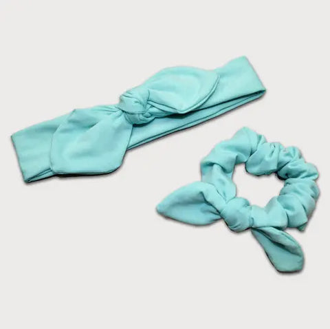 The Goodnighties Matching Knotted Bow Headband & Scrunchie set features stylish, coordinating hair accessories in light blue, displayed on a plain white background.