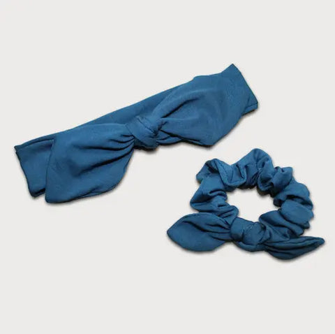 The Goodnighties Matching Knotted Bow Headband & Scrunchie set in blue fabric features bow-like details, making stylish hair accessories, displayed on a light background.