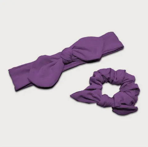 The Goodnighties Matching Knotted Bow Headband & Scrunchie set in purple features a stylish headband and a soft scrunchie with a small bow, both shown on a white background.