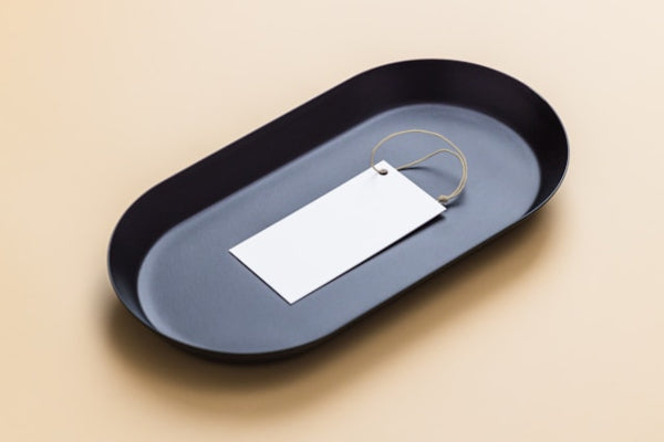 Black oval tray with a white tag on a beige background
