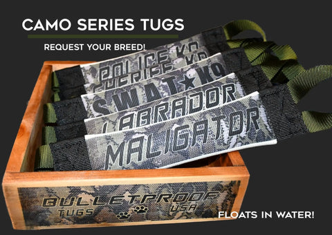 A wooden box from Bulletproof Pet Products Inc holds five camo Labrador Fire Hose Training Tugs labeled POLICE K-9, SWAT, LABRADOR, and MALIGATOR. CAMO SERIES TUGS—request your breed! Heavy-duty gear floats in water.