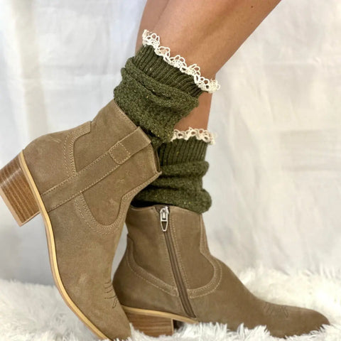 A person wears Catherine Cole’s BOOTIE Lace Slouch Socks in Olive with tan suede ankle boots featuring a low chunky heel, standing on a white textured surface against a white background.