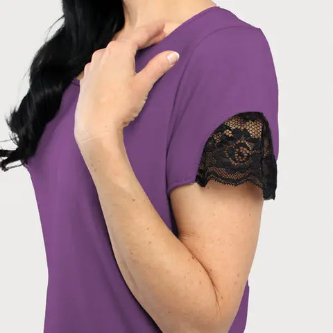 A person wearing the Goodnighties Lace Accent Scoop Neck Tee in purple with black lace sleeve trim, seen from the side with a hand on their shoulder—American-made, ideal for sleepwear or moisture-wicking loungewear.