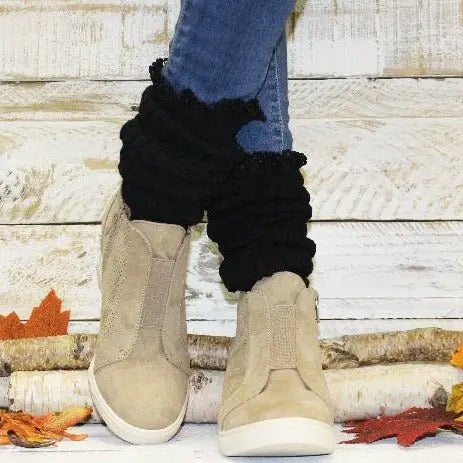 A person in blue jeans and Catherine Cole LACE Topped Ultimate Slouch Socks in black stands on wood planks scattered with autumn leaves and birch logs—a perfect showcase of cozy women’s fashion accessories.