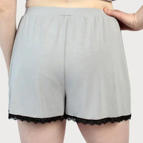 A person models light gray Lace Trim Tulip Shorts by Goodnighties, shown from the back with a hand on their hip—American-made sleepwear designed for comfort and style.