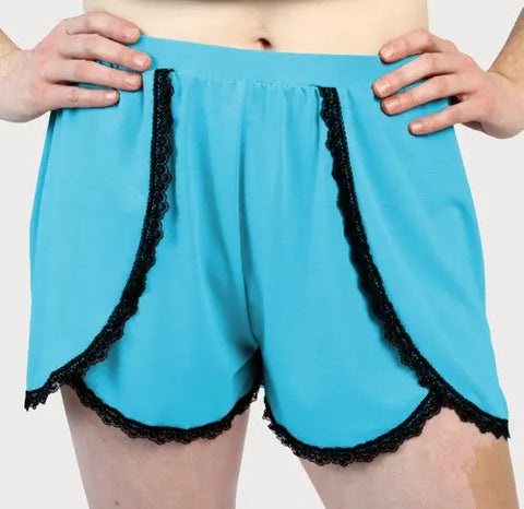 Model in light blue Goodnighties Lace Trim Tulip Shorts with black lace along curved front edges, standing hands on hips against a plain background—ideal American-made sleepwear for stylish relaxation.