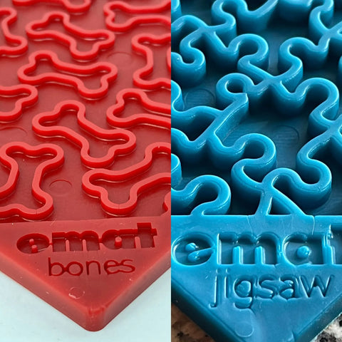 Close-up of SodaPup’s Large Blue Jigsaw & Large Red Bones EMat Lick Mat Bundle: the red mat features bone-shaped grooves, while the blue mat has jigsaw puzzle grooves—both designed for dog enrichment and slow feeding.