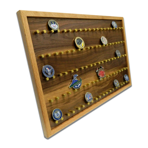 The ORIGINAL Brass Casing Challenge Coin Display - Large by Legacies of America Woodworking Company showcases colorful coins on brass pegs. American-made, it features a dark wood backing, lighter frame, and is shown from an angled view.