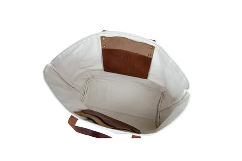 The Urban Southern Large Canvas Tote, made in the USA, features brown full-grain leather handle accents and an interior pocket, shown from above on a white background.