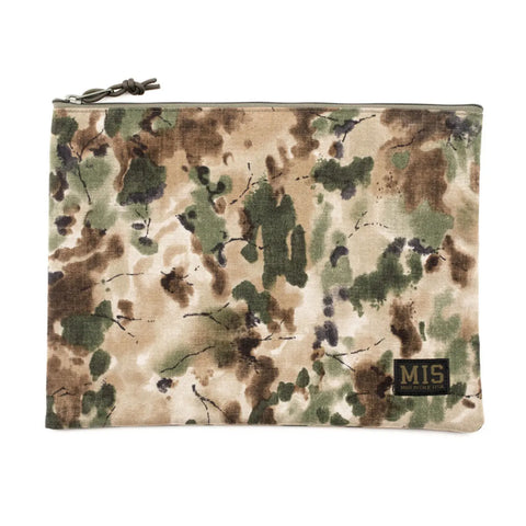 The MIS Tool Pouch L - Covert Woodland is a zippered pouch made from water-resistant Cordura nylon with a green, brown, and beige camouflage pattern and a small black MIS patch in the bottom right corner.