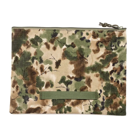 The MIS Tool Pouch L - Covert Woodland is a rectangular, water-resistant pouch with a zipper, featuring green, brown, and beige camouflage, a horizontal green strap near the bottom front, made in the USA and shown on a white background.