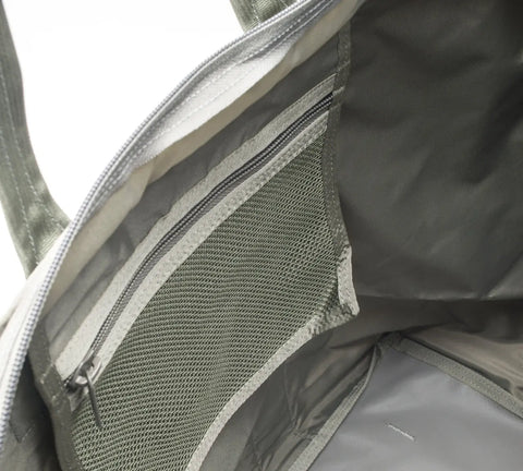 Close-up of the interior of the MIS Super Tote Bag - Foliage, featuring a zippered mesh pocket, an additional inner compartment, and gray fabric lining with a partially open zipper.