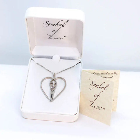 The Large Soulmate Heart Necklace by Symbol of Love Jewelry, crafted from .925 sterling silver with a clear cubic zirconia charm (1½ x 1¼) on an 18 chain, is displayed in an open white jewelry box with a Symbol of Love card beside it.
