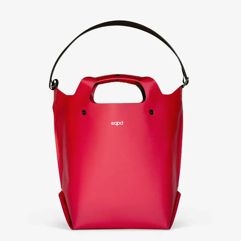 The eqpd LastBag - Shoulder is a bright red, structured modern handbag with short handles and a detachable black shoulder strap. Ideal for everyday use, it features a small white logo on the front and is set against a plain white background.