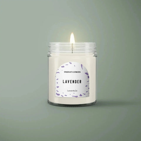 The Lavender - Signature Candle by Sawdust & Embers is a handcrafted soy candle in a clear glass jar with a “Lavender” label featuring purple leaf art—a premium home fragrance to enhance any room.