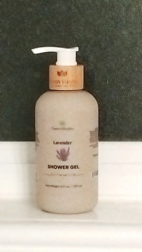 A bottle of Forev'Herbs Lavender Shower Gel with a wooden pump sits on a white bathroom shelf against a dark wall, its label displaying a lavender flower illustration that suggests the calming benefits of lavender essential oil.