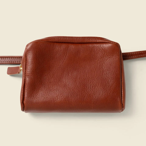 The CASUPO Leather Fanny Pack - Chocolate is a small, rectangular brown hip bag made from sustainable leather with a zipper closure and attached strap, shown against a plain light beige background.