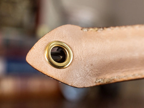 Close-up of the Leather Pen Sleeve for G2 Pens by KC Laser Co, showing detailed stitching and a brass grommet. Handcrafted in the USA by Crafted x KC Laser Co; features a blurred background.