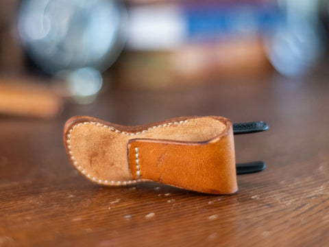 A compact, brown veg-tanned leather tool holster for Knipex 4 XS pliers by KC Laser Co lies on a wooden surface, with visible stitching and a blurred background.