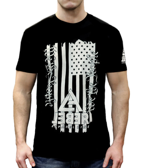 A man wears The Founder T-shirt from Leber Apparel Line, featuring a distressed American flag, bold REBEL lettering, and gothic text—ideal for patriotic style enthusiasts.