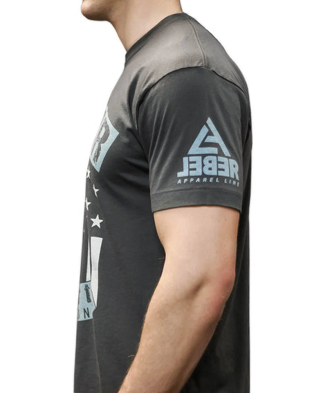 A person wears The Commander, a black t-shirt by Leber Apparel Line, featuring a triangle logo on the sleeve, shown side view against a white background to showcase this quality American-made apparel.