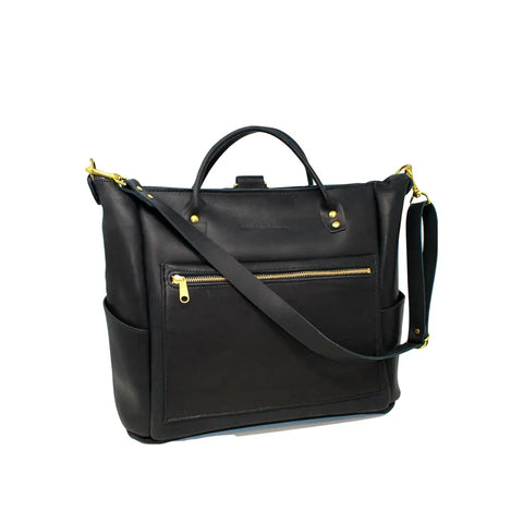 The Urban Southern Legacy Backpack Tote in black leather features gold hardware, a top handle, convertible straps, a front zip pocket, and side pockets—highlighting classic heritage style against a white background.