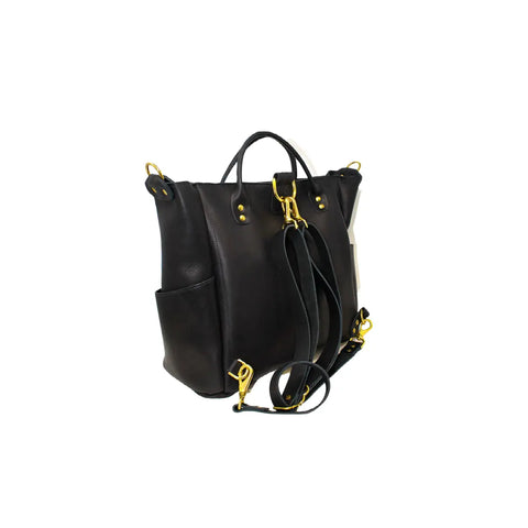 The Legacy Backpack Tote by Urban Southern features black leather, gold hardware, dual handles, convertible straps, and side pockets—an elegant reflection of the brand’s heritage style, displayed against a white background.