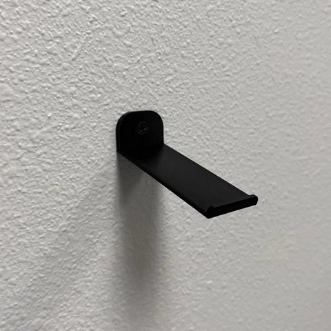 The Chatelet Manufacturing Collectible Wall Display, compatible with LEGO Speed Champion racecars, is mounted horizontally on a textured white wall as a sleek Side Car Display Wall Mount (Side Profile), casting a shadow below it.