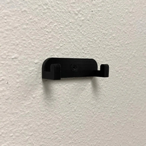 The Chatelet Manufacturing Collectible Car Wall Mount, compatible with Lego Technic Lamborghini Huracán Tecnica 42161, features a black plastic two-prong hook for vertical display and is secured to a white wall with a central screw. Made in USA.