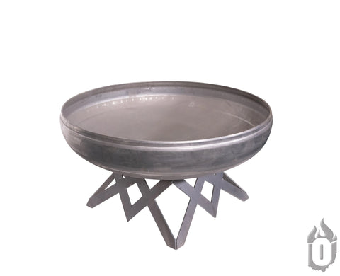 The Ohio Flame Liberty Fire Pit With Angled Base is a large, round American fire pit featuring a wide, shallow carbon steel bowl and a sturdy geometric metal base, shown against a white background. Made in the USA.