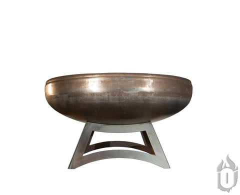 The Ohio Flame Liberty Fire Pit With Hollow Base (Made in USA), a large round steel pit with a smooth brushed finish, sits on a sturdy angular base against a plain white background. The Ohio Flame flame logo appears in the lower right corner.