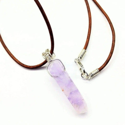 The Silver Wrapped Light Amethyst Gemstone Point Leather Necklace by Alexa Martha Designs features a brown leather cord, a sterling silver wire wrapped light amethyst point pendant, and is finished with a silver clasp.