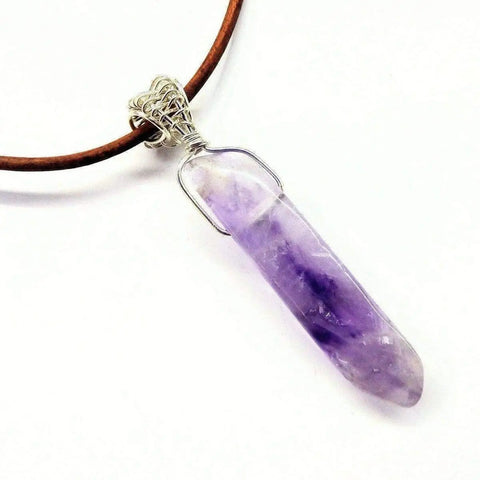 The Silver Wrapped Light Amethyst Gemstone Point Leather Necklace by Alexa Martha Designs features a brown leather cord and a sterling silver-wrapped light amethyst pendant with purple and white hues.