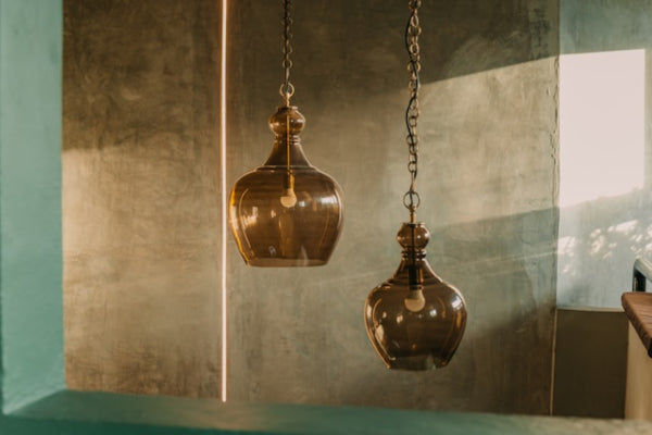 Two hanging brass lanterns against a textured wall.