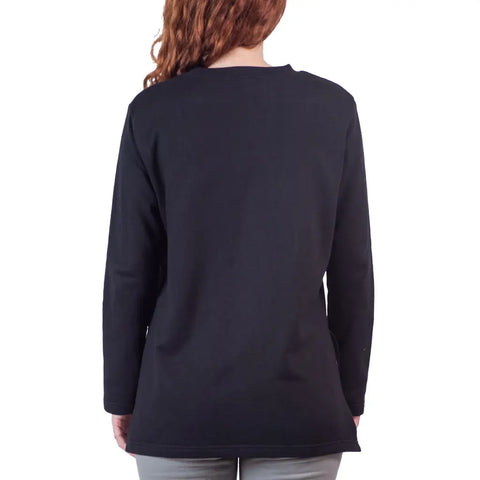 A person with long, wavy brown hair is seen from behind wearing the Flint Street Fleece Pullover by Spiritex | Sustainable Apparel in black, paired with gray pants, standing against a plain white background.