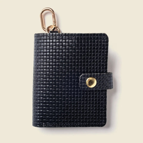 The CASUPO Wallet With Snap and Key Ring - Black Limited Edition features eco-friendly textured leather, a gold snap button, and a gold carabiner, shown on a light beige background.