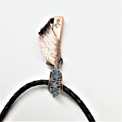 The Memorial Birthstone Angelwing Necklace-Limited Special Edition 2020-2024 by Alexa Martha Designs features a custom copper wing, blue crystal accents, and stamped rod on a black braided cord—an elegant tribute to honor loved ones.