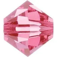 A faceted, bicone-shaped pink crystal bead reflects light against a white backdrop—ideal for adding to the Alexa Martha Designs Memorial Birthstone Angelwing Necklace-Limited Special Edition 2020-2024.