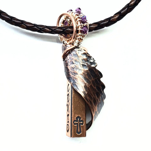 The Memorial Birthstone Angelwing Necklace-Limited Special Edition 2020-2024 by Alexa Martha Designs features a braided cord, copper feather, personalized copper rod stamped with COVID and a cross, plus rings with purple beads—a unique Covid memorial keepsake.