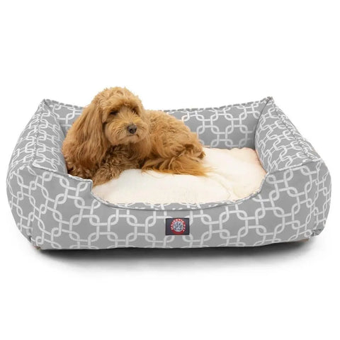 A fluffy light brown dog relaxes on a cream cushion inside the Majestic Pet Links Contemporary Lounge Bed, a gray rectangular bed with premium fiberfill and a white geometric pattern.