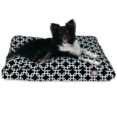 A black and white dog lounges on the Majestic Pet Links Rectangle Dog Bed, featuring a white geometric pattern and a removable cover for easy cleaning, as it relaxes with its mouth slightly open.