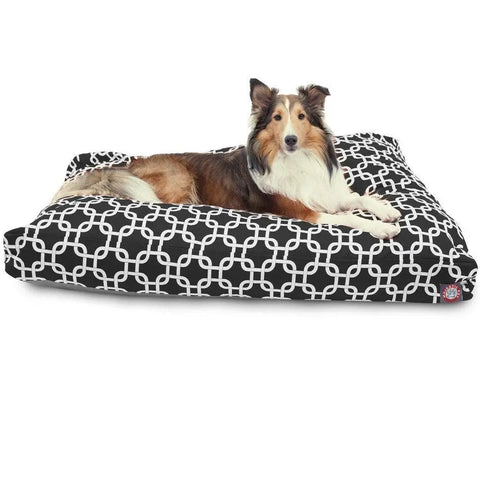 A brown and white dog lies on the Majestic Pet Links Rectangle Dog Bed, featuring a white geometric design. This washable bed offers comfort, and the dog looks relaxed and alert while facing forward.