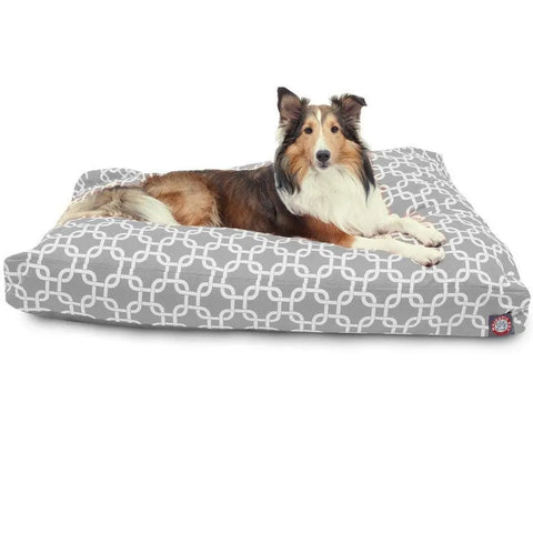 A brown and white long-haired dog lies on the Majestic Pet Links Rectangle Dog Bed, which has a gray and white geometric pattern and a washable cover.