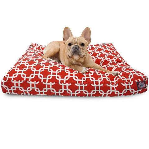 A light brown French Bulldog lies on the Majestic Pet Links Rectangle Dog Bed, which has a red and white geometric pattern, premium polyester fiber fill, and a washable cover, looking directly at the camera.