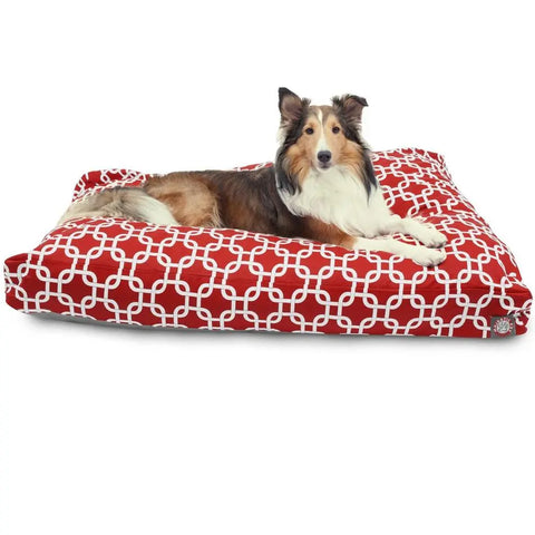 A Shetland Sheepdog lies on the Majestic Pet Links Rectangle Dog Bed, featuring a white geometric pattern and filled with premium polyester fiber, looking at the camera against a plain white background.
