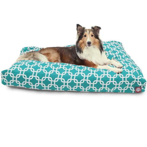 A Collie with brown, white, and black fur lies on the Majestic Pet Links Rectangle Dog Bed, which features a teal and white geometric pattern, premium polyester fiber fill, and a washable cover for lasting comfort.
