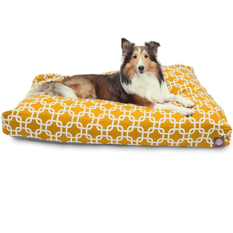 A fluffy brown and white dog lies on the Majestic Pet Links Rectangle Dog Bed, which features a washable cover in mustard yellow with a white geometric pattern.
