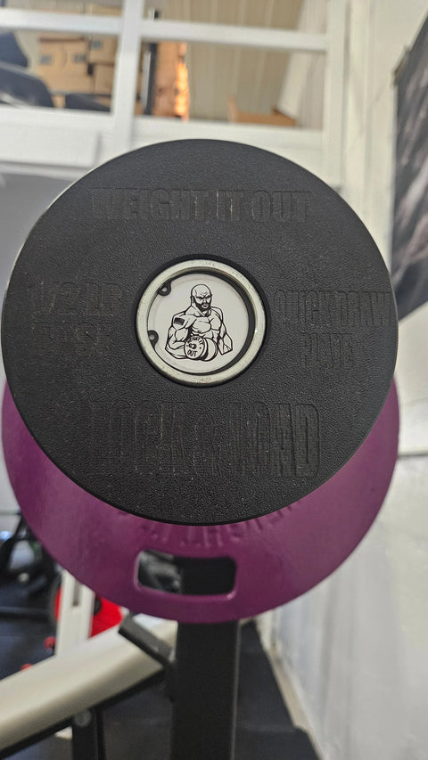 A close-up of Weight It Outs Lock and Load Revolver Micro Loading Plates, featuring a cartoon muscular man with a barbell—perfect customizable gym gear for precise weight adjustments.